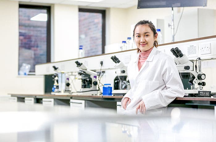 Student smiling in lab coat