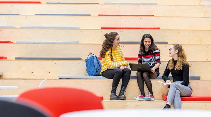 Three female student sitting and talking on campus