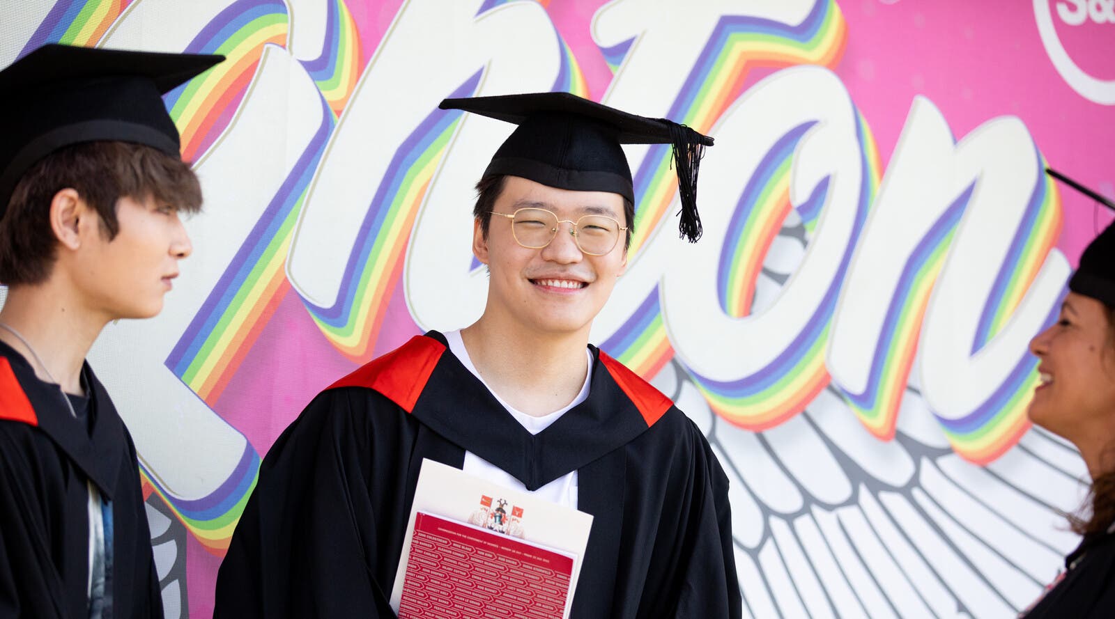 A student smiling in a graduation cap and gown.