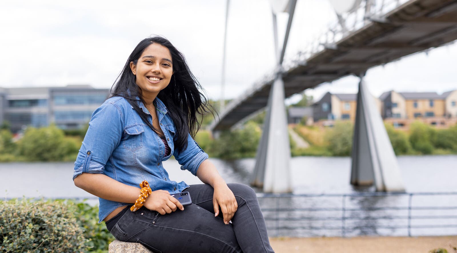 Student smiling in front of bridge and river
