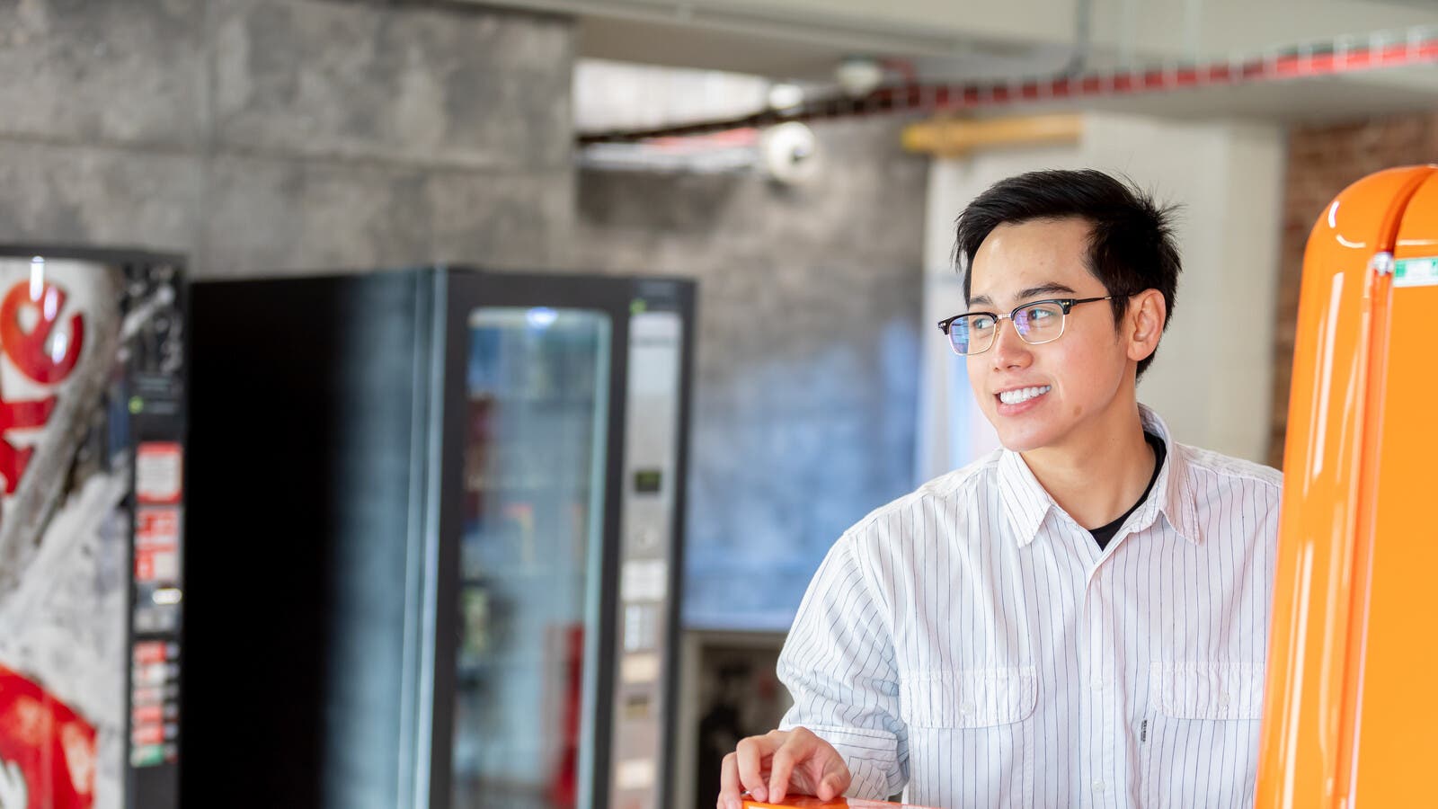 A student smiling on campus in front of vending machines