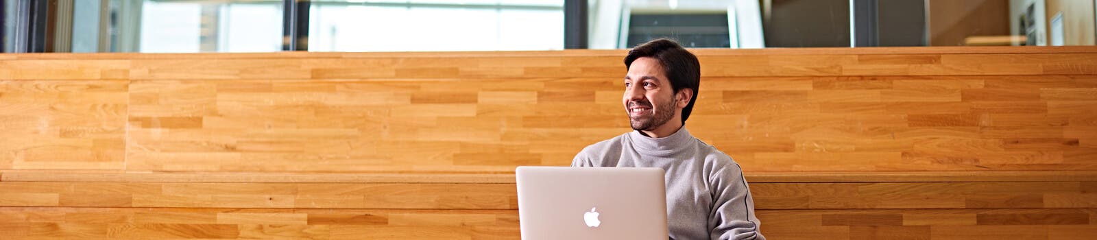 Student smiling on campus with laptop