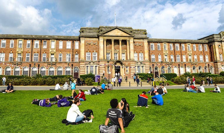 Students sitting on grass outside campus
