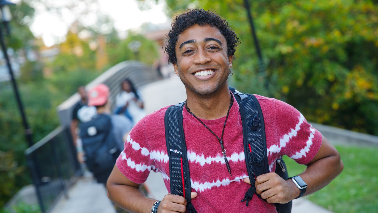 Student walking and smiling with backpack on