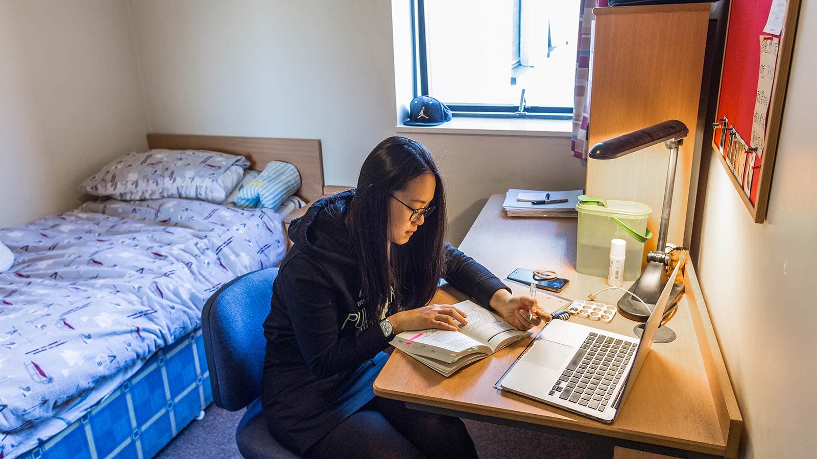 Student studying at bedroom desk in accommodation