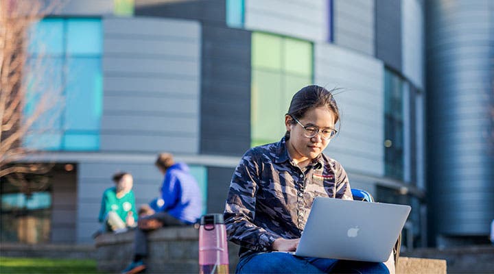 Student working on laptop outside campus