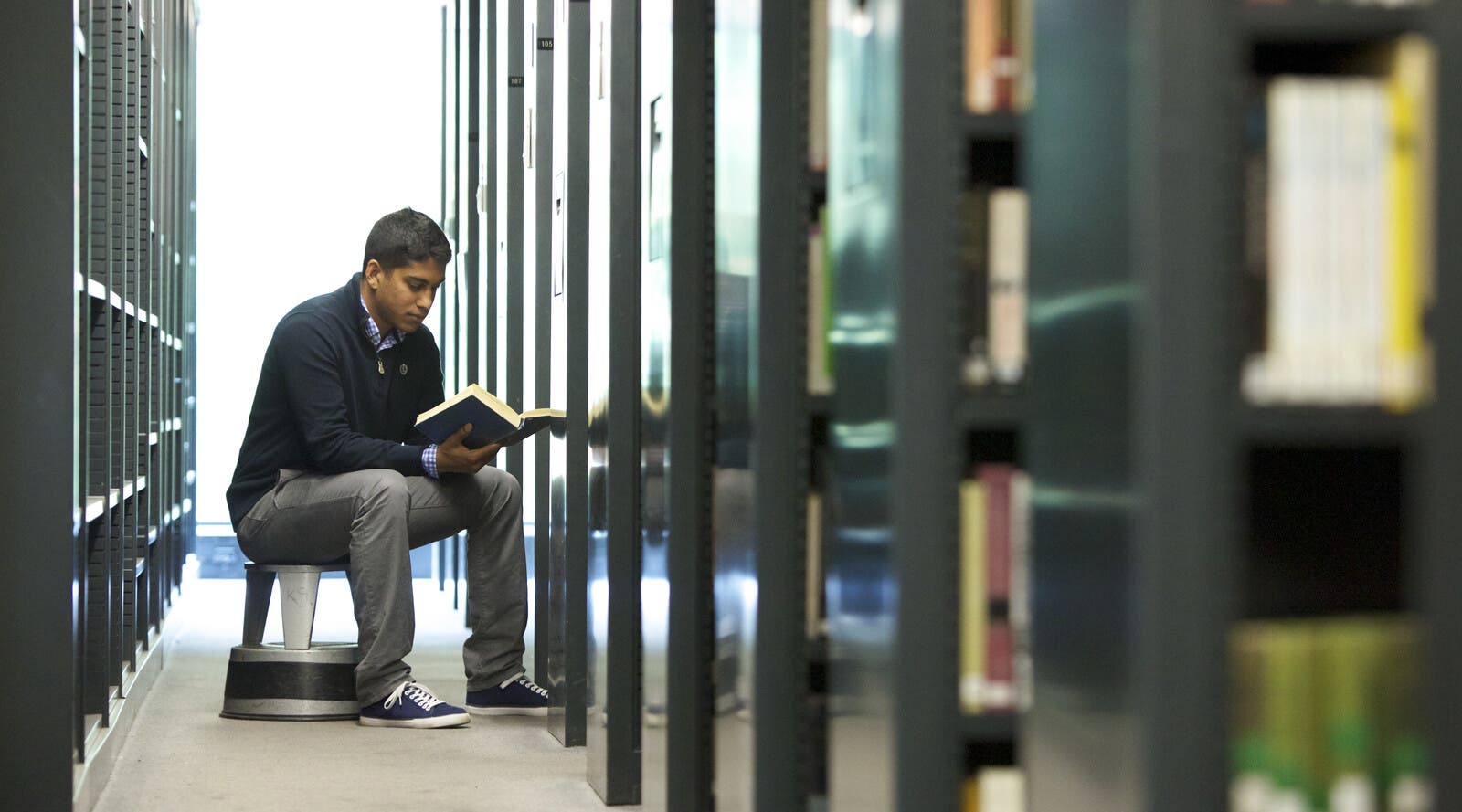 student sitting down and reading a book in the library