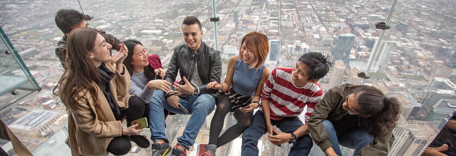 A group of students sitting and laughing in a glass building