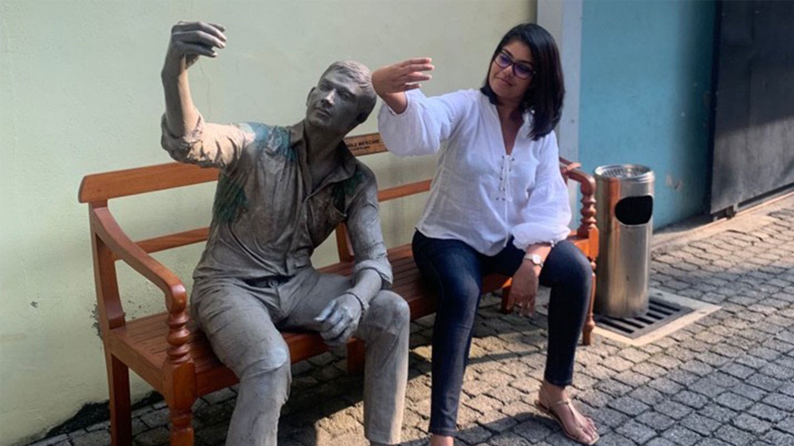 A staff member taking a selfie with a statue.
