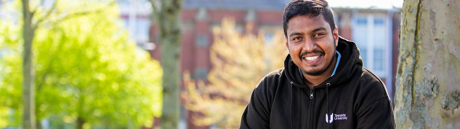 Student smiling outside wearing Teesside University hoodie