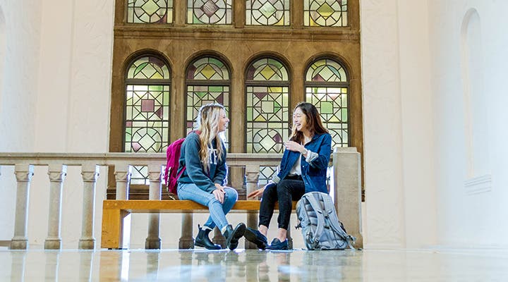 Students talking in front of stained-glass windows