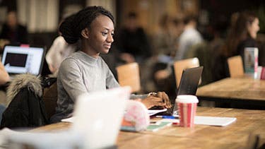 Surrey student working on laptop in cafeteria