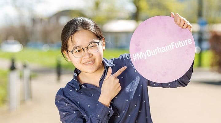 指着 "#MyDurhamFuture" 标志的学生