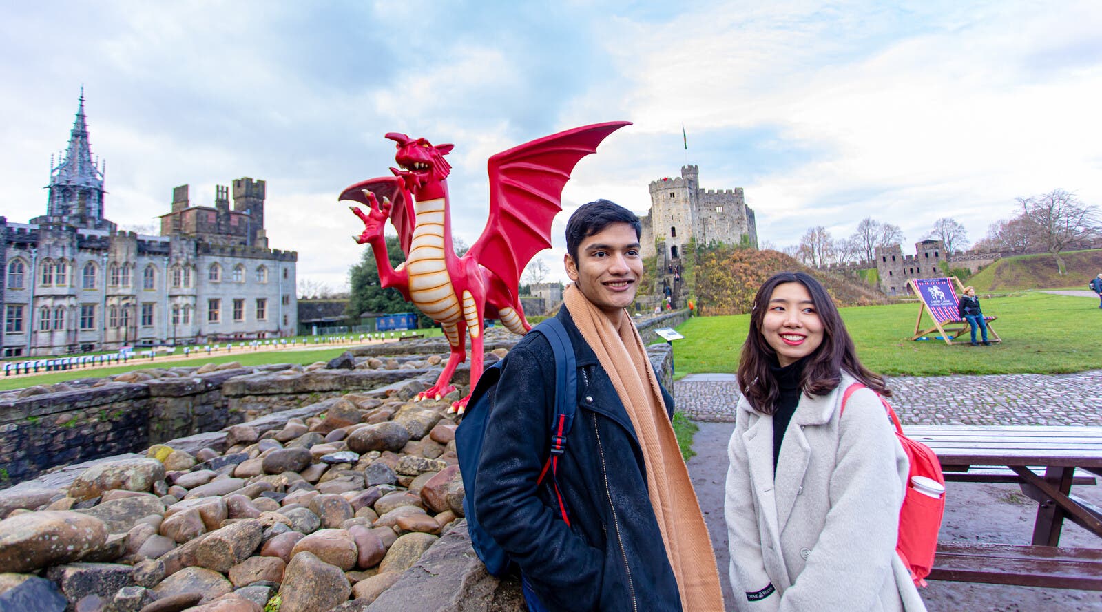 Students smiling in front of model dragon and castle