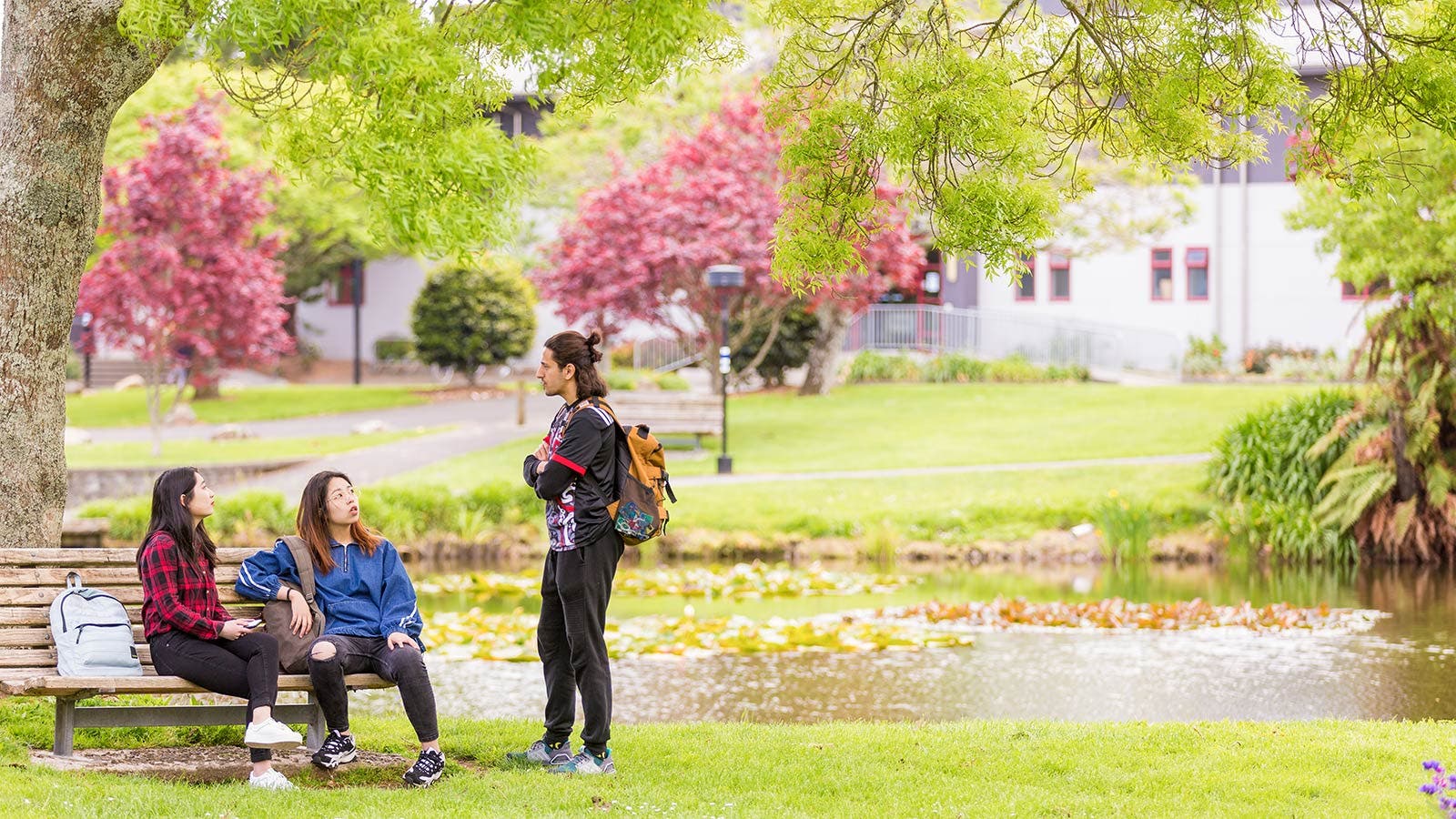 Students sitting and talking on bench by river 