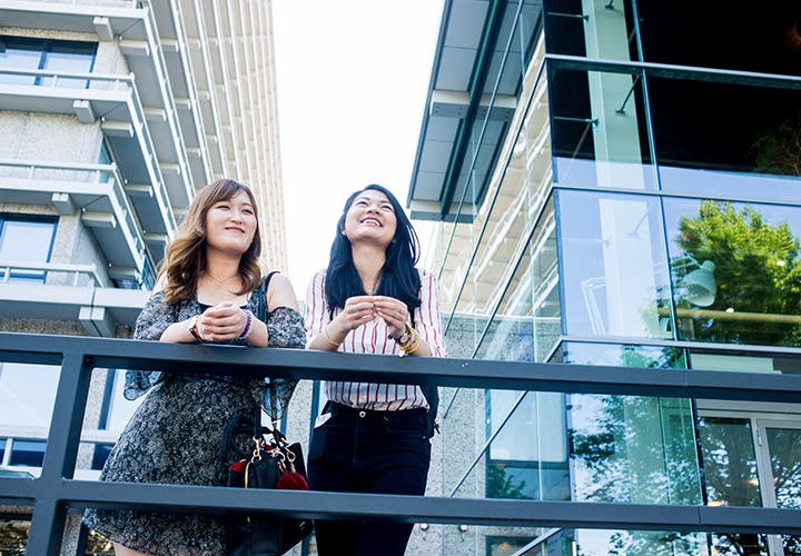 Students smiling and leaning on balcony