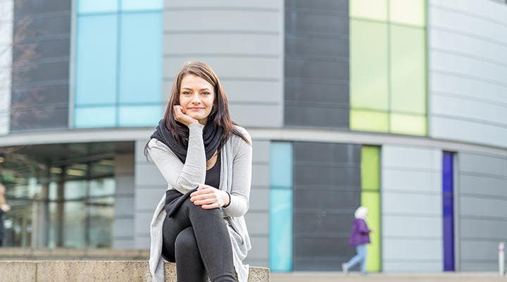 Student sitting on steps in front of campus