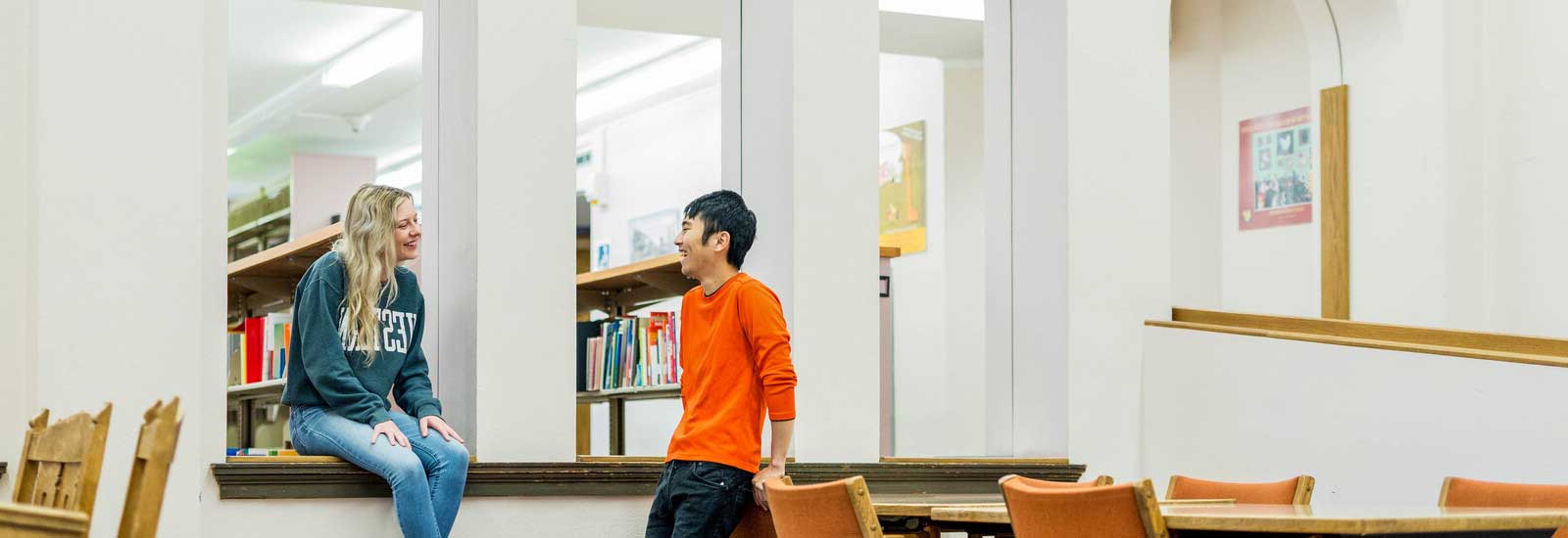 Two students talking in library