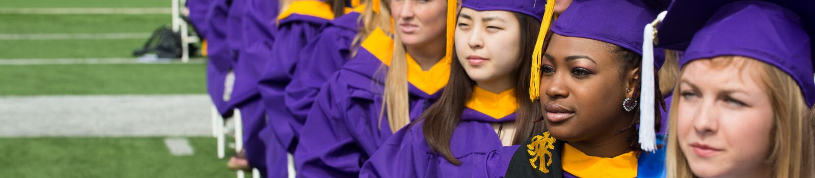 JMU graduates lined up on a sports field