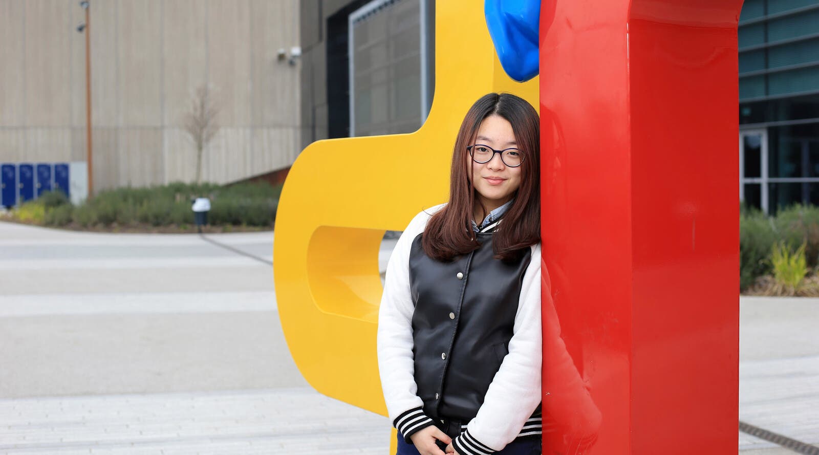 Student leaning on sculpture outside campus