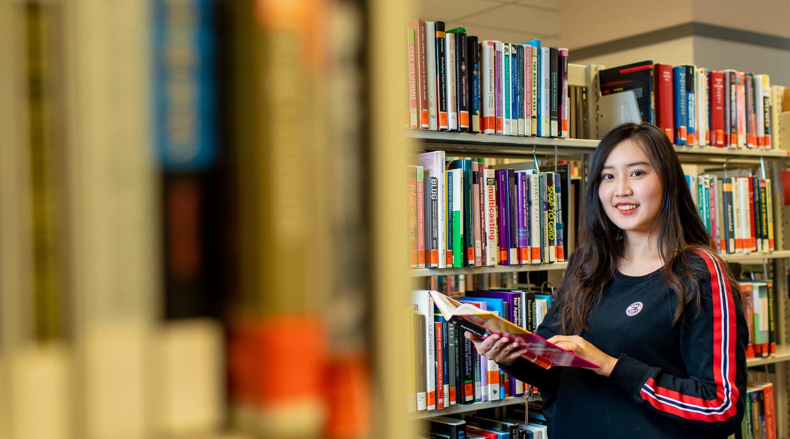 Student holding book in library