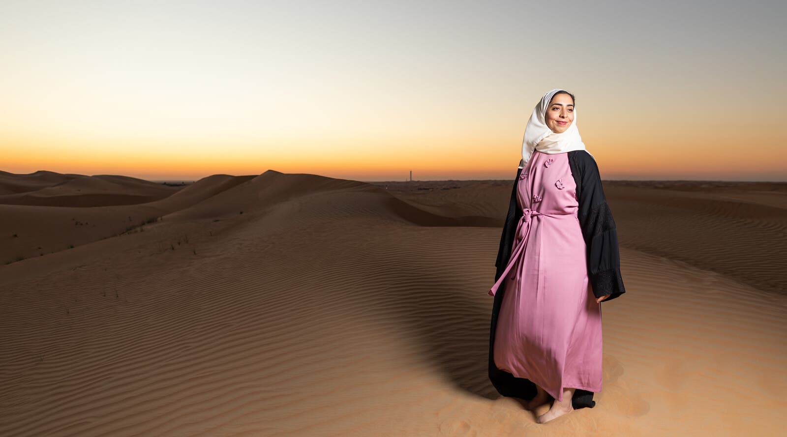 Dalia, stood in the desert with the sun setting.