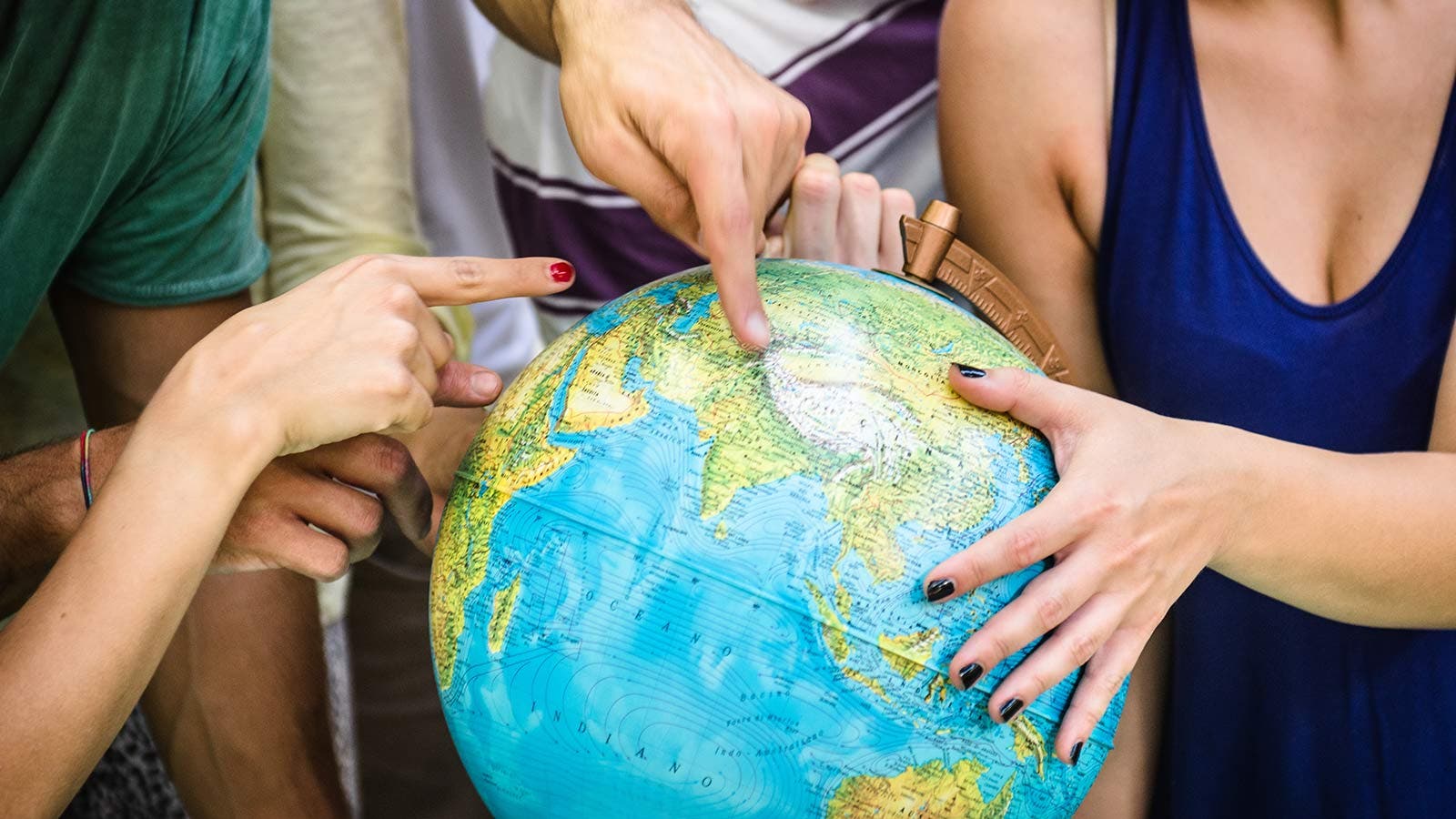 Hands holding and pointing at a globe