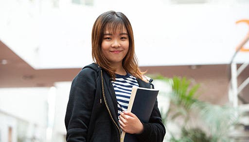 Surrey student holding textbook outside campus
