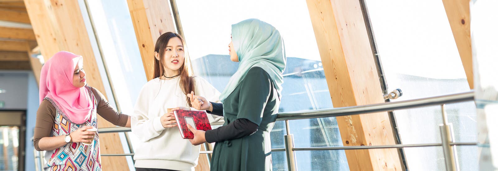 三名学生靠在校园内的栏杆上