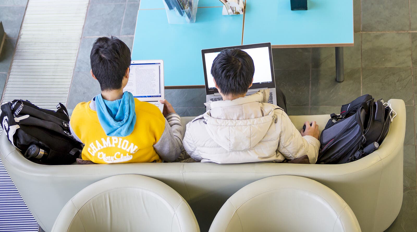 Students on laptops and sitting on a sofa