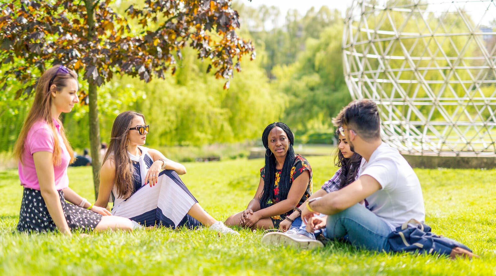 Students sitting on grass outside campus