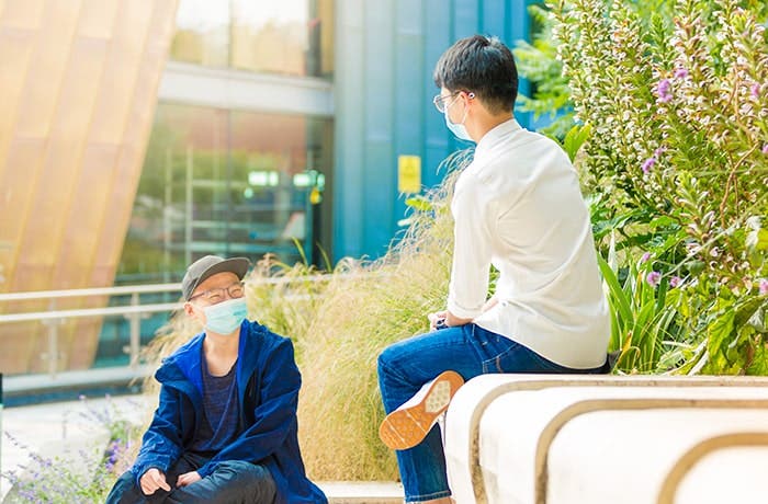 Students sitting outside campus wearing face-masks