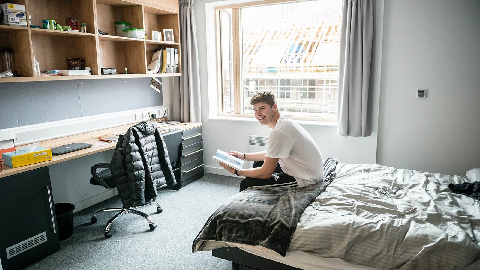 Surrey student reading on bed in accommodation