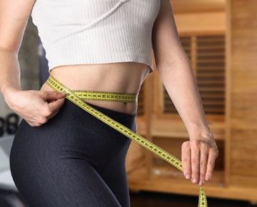 A fit person measuring their waist with a tape measure.