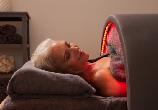 Older woman using the Sunlighten Solo System portable infrared sauna, lying comfortably under red light therapy.