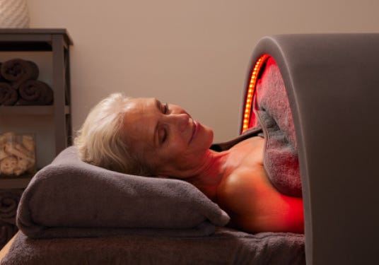Older woman using the Sunlighten Solo System portable infrared sauna, lying comfortably under red light therapy.