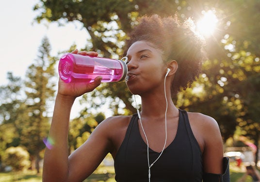 Woman drinking water while exercising outside