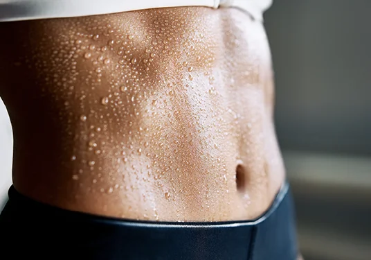 Close-up of toned stomach with sweat after calorie-burning infrared sauna session