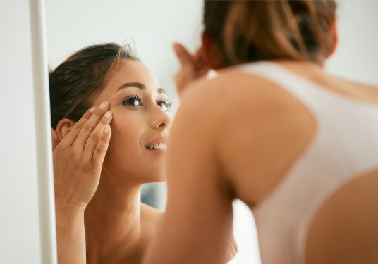 Woman looking at her skin in the mirror