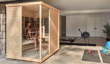 A couple relaxes in a Sunlighten mPulse Discover infrared sauna in their home gym.