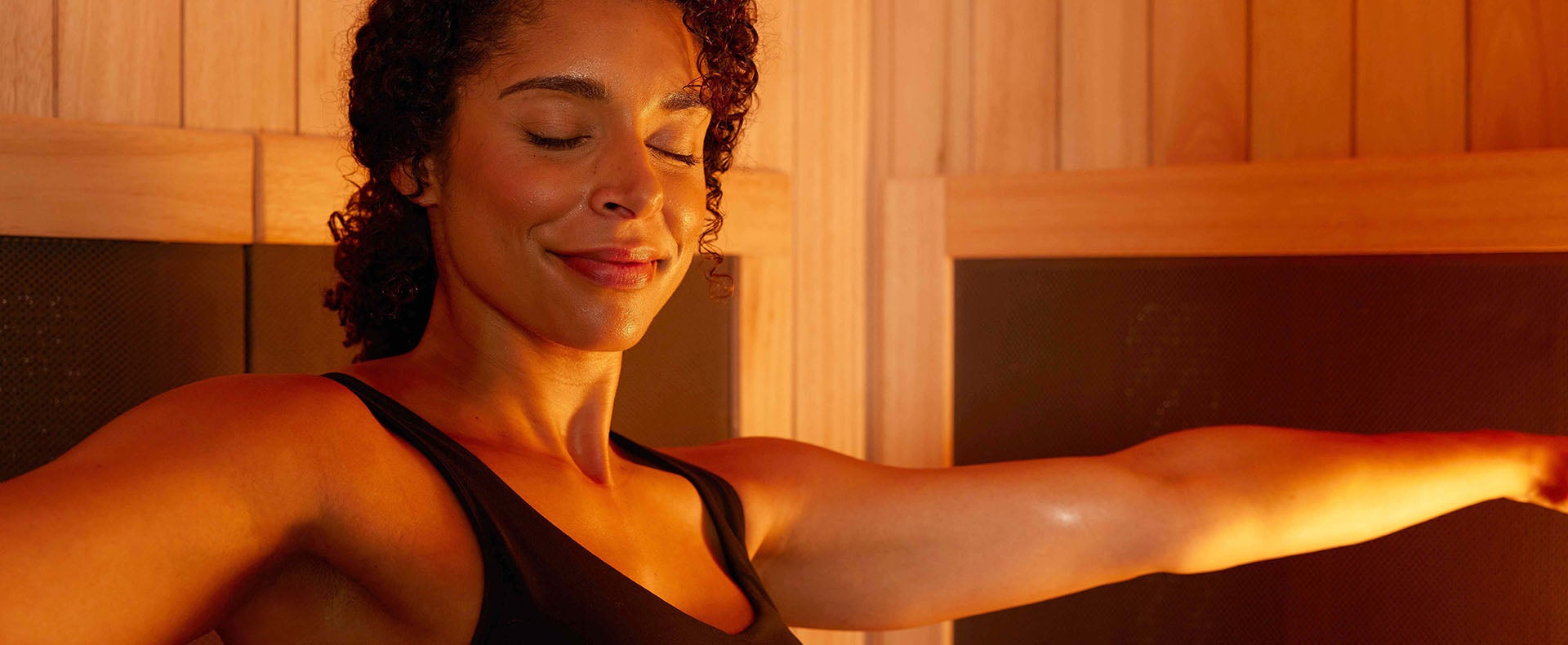 Woman enjoying stretching arms in sauna