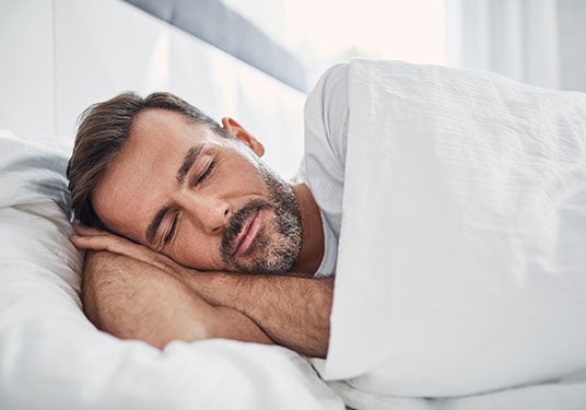 A man smiling while restfully sleeping.