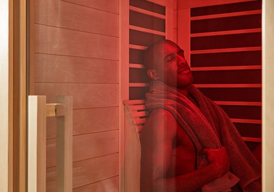 A man sits with his eyes closed in a Sunlighten infrared sauna.