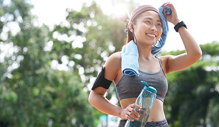 Woman wiping sweat off her face with a towel after exercising