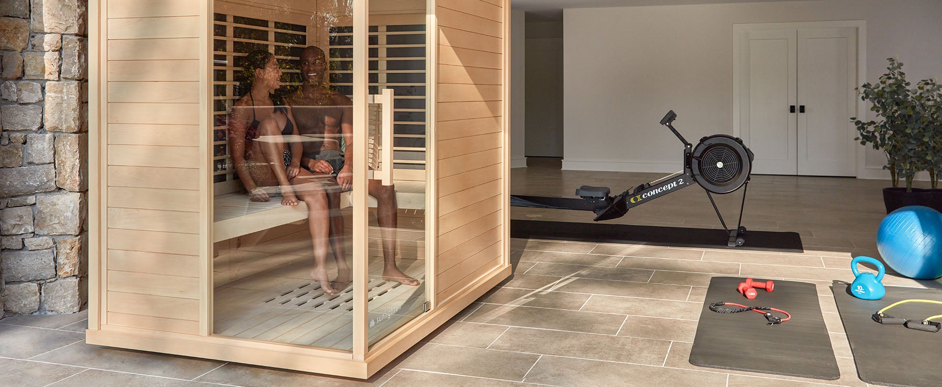 A couple relax in a Sunlighten mPulse Discover infrared sauna in their home gym.