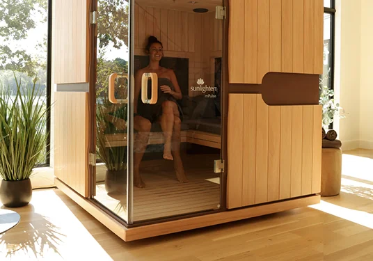 Modern Sunlighten infrared sauna with woman inside enjoying calorie-burning and recovery benefits