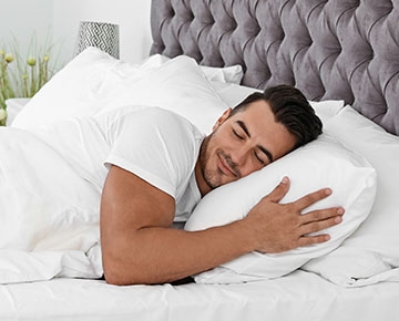 A man sleeps in bed after using a Sunlighten infrared sauna.