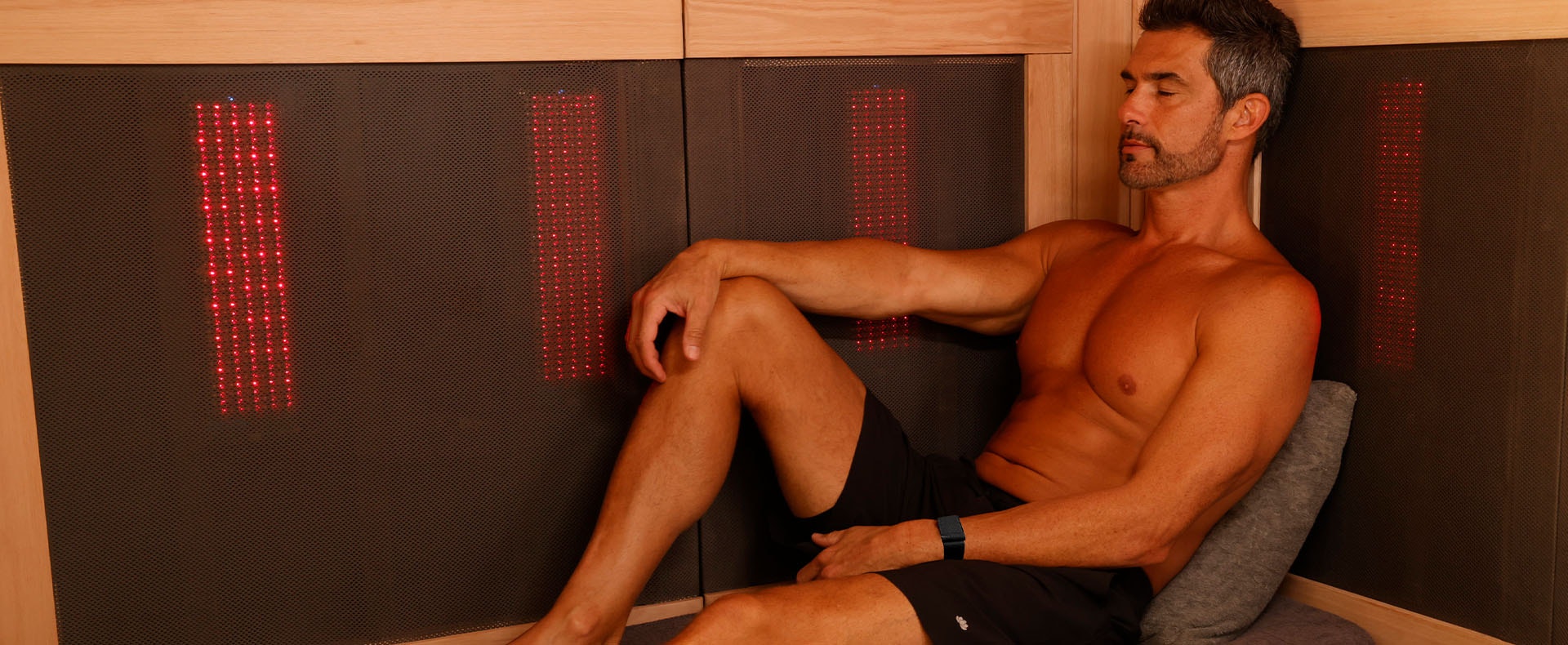 A man relaxes in a Sunlighten infrared sauna with red light.