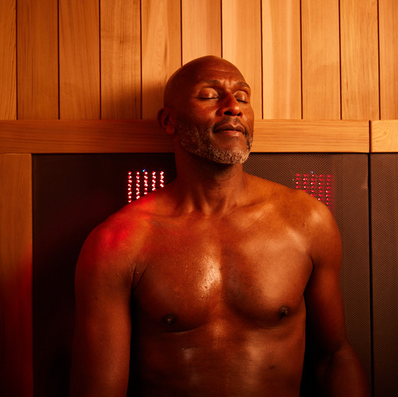 A man relaxes in a Sunlighten mPulse Smart Sauna with red light. 