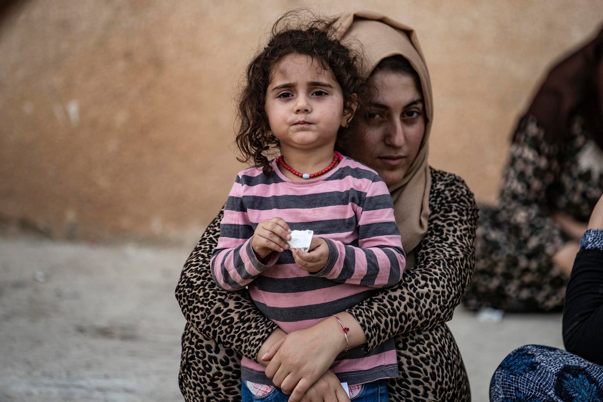 A woman is holding a young girl by the waist.